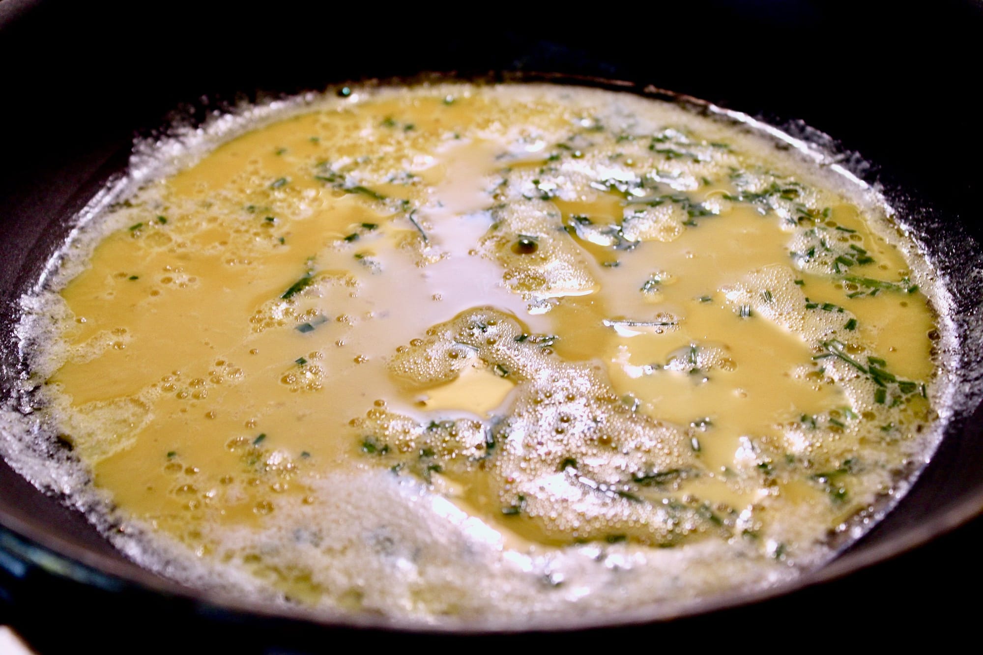 Eggs and chives in pan.