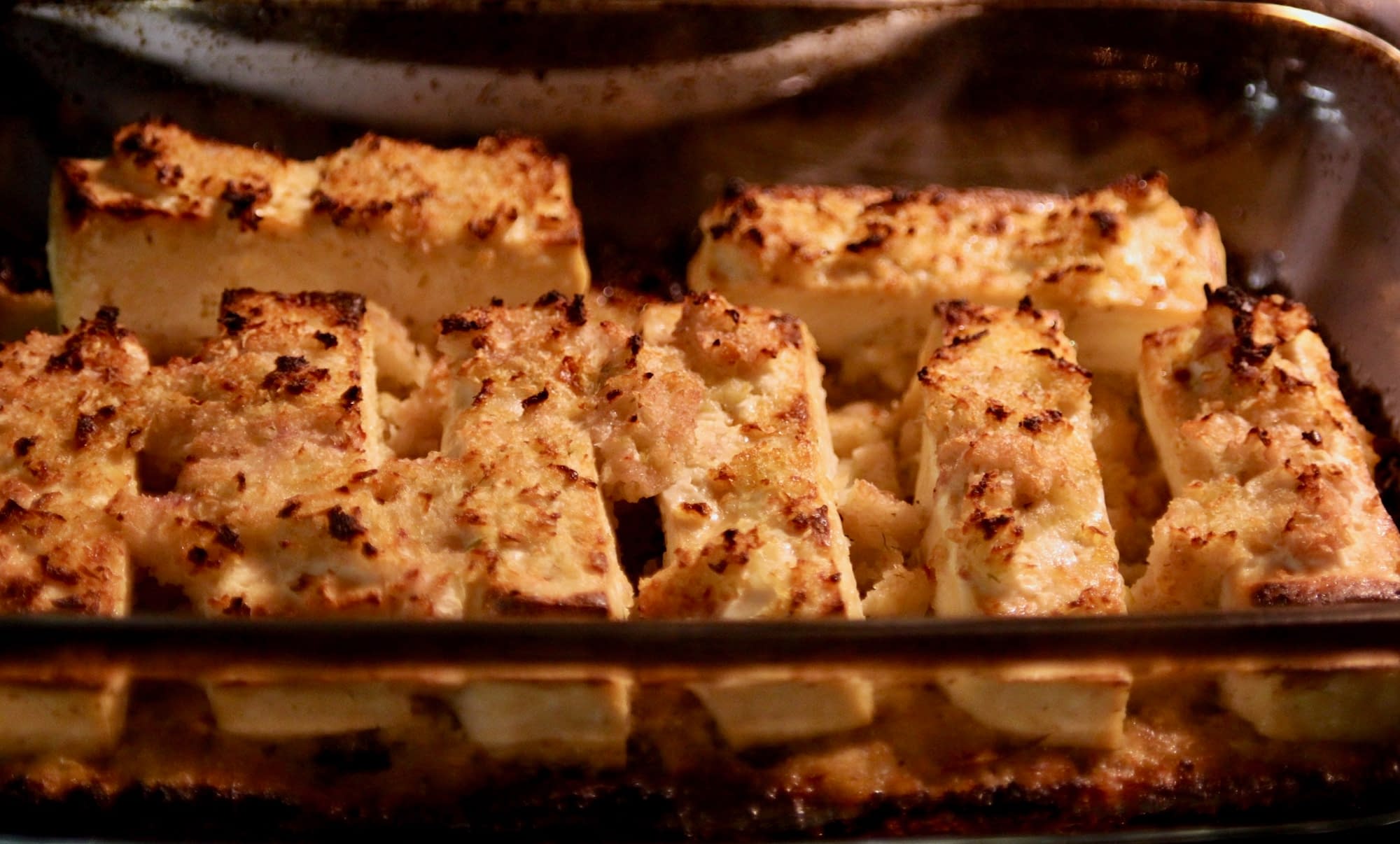 Roasted tofu turning golden brown in the oven and ready to serve on top of the beans and kale