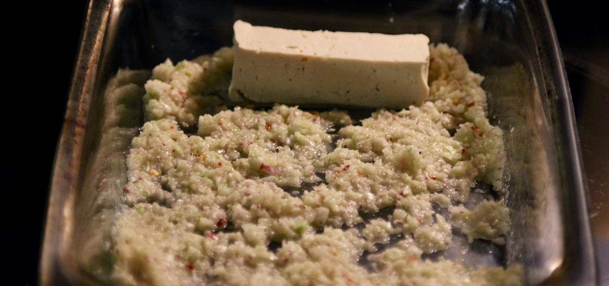 Adding onion and fennel mixture to the tofu.