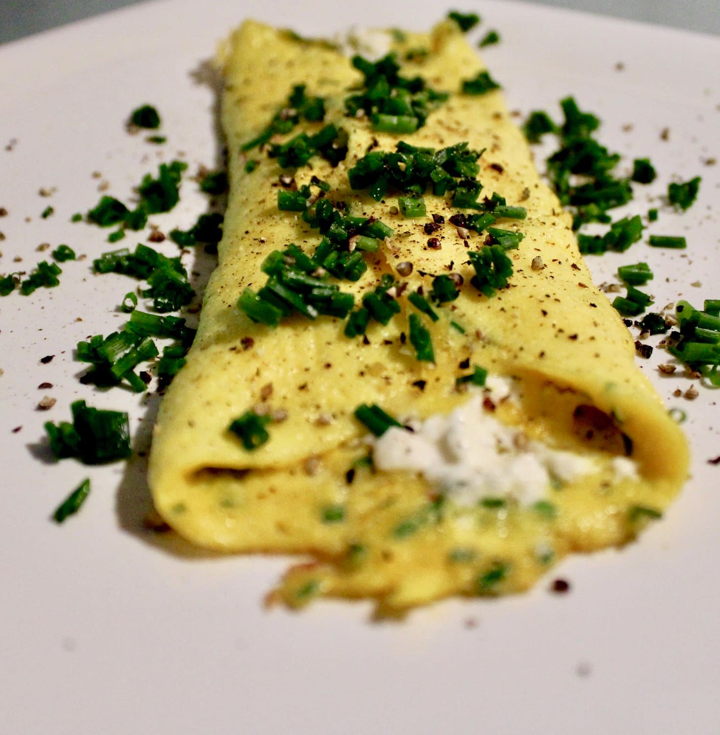 French omelette garnished with chives and black pepper.