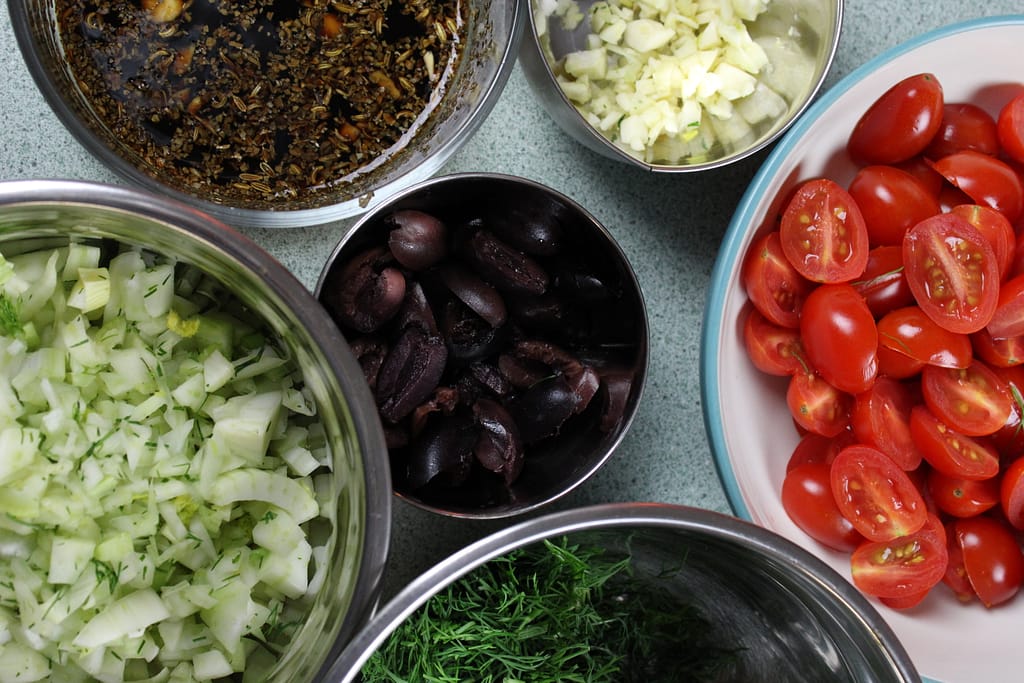 Ingredients like fennel, tomato, garlic, and olives for a tomato relish.