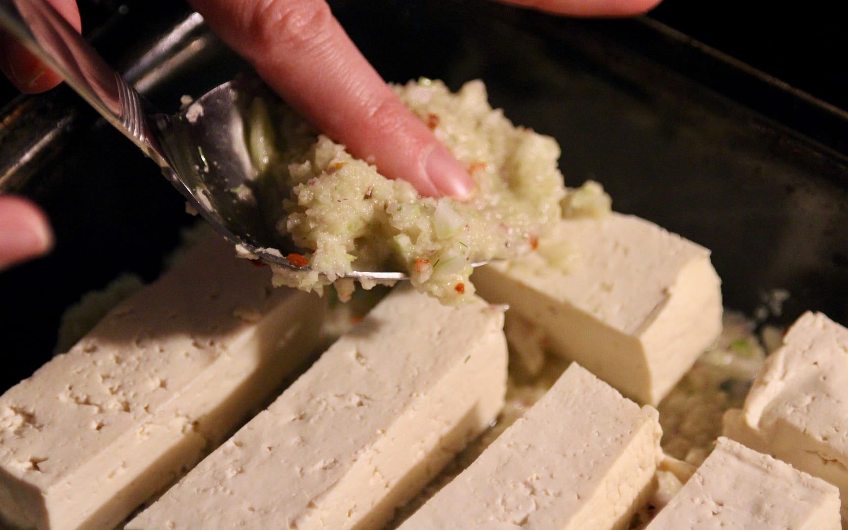 Adding the onion and fennel mixture to the tofu.