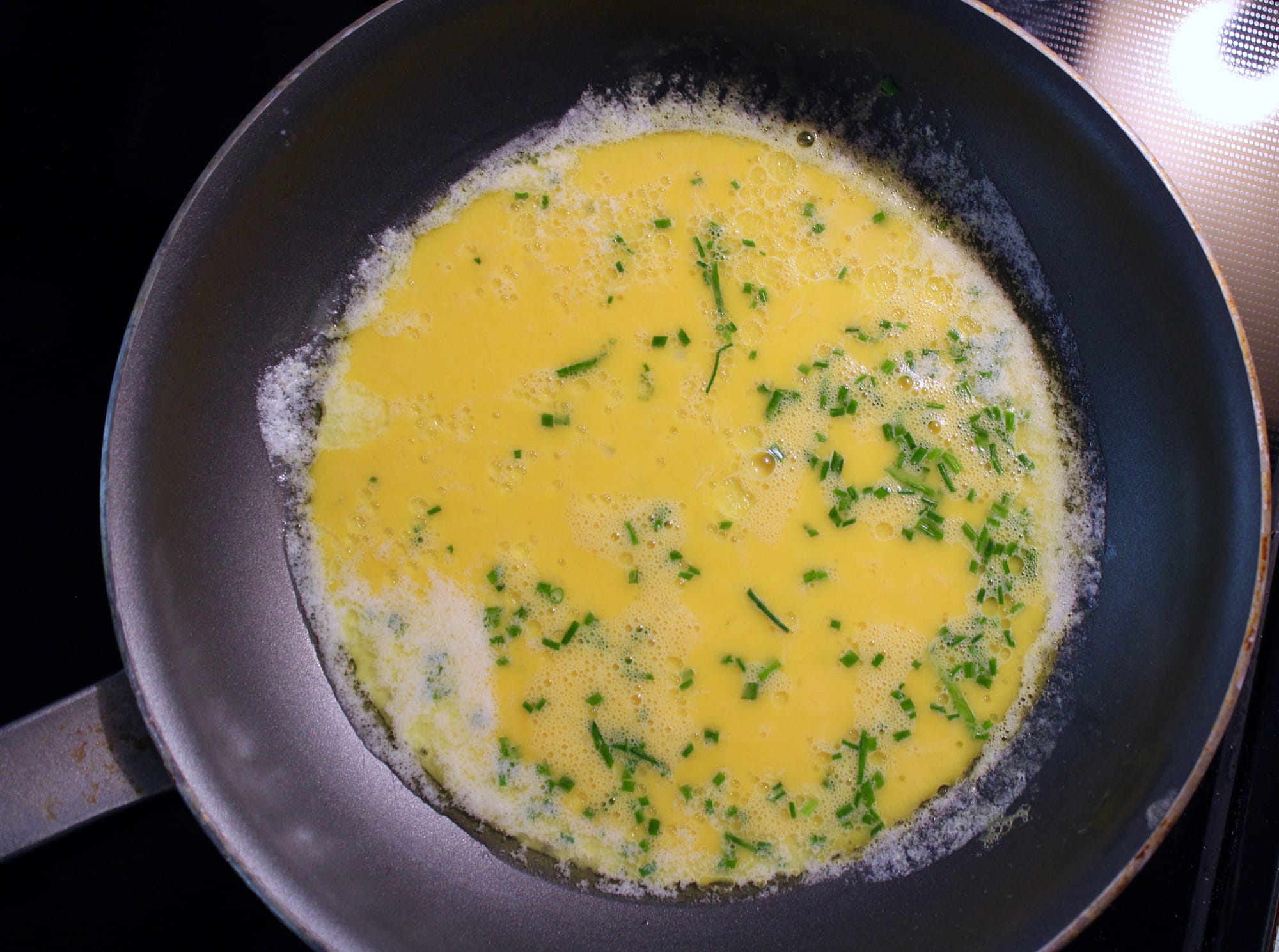 Eggs and chives in skillet for french omelette.